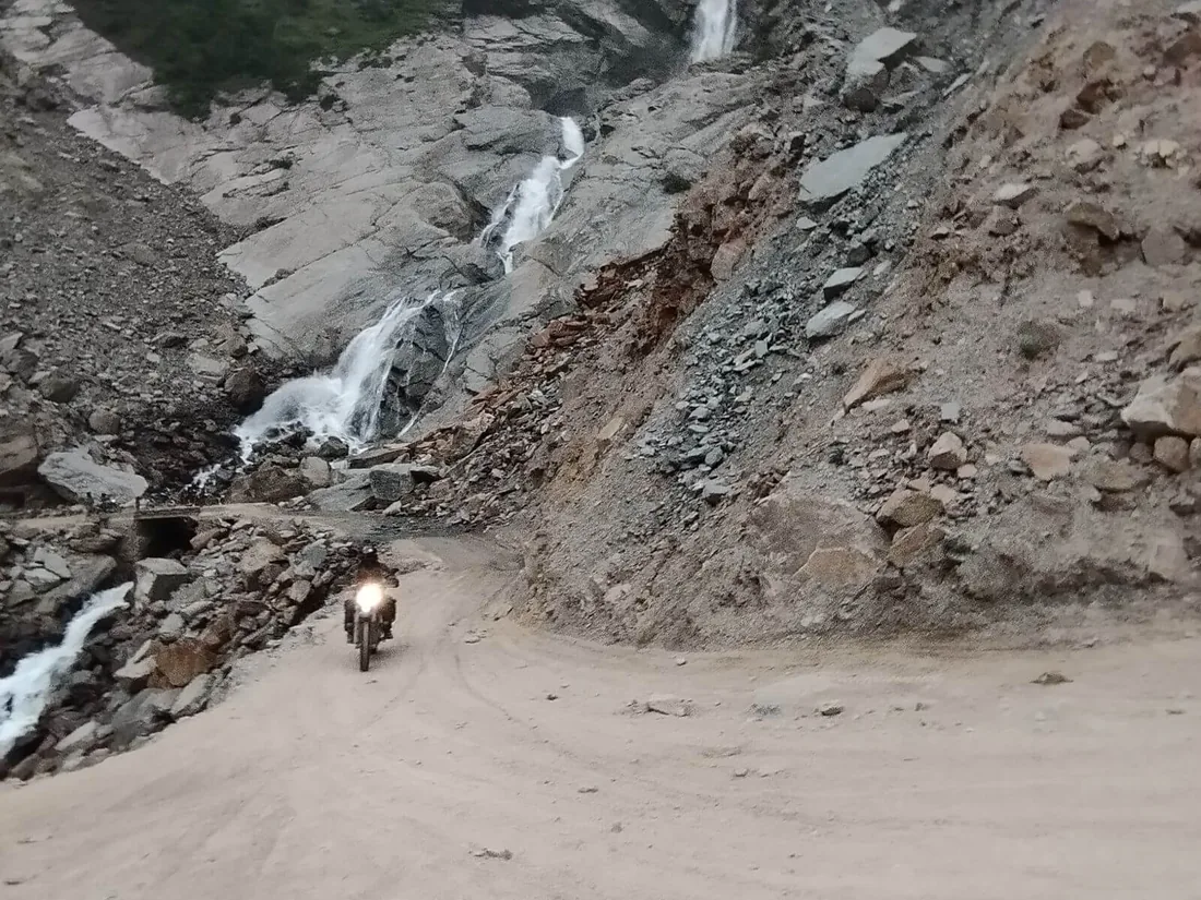 Route de montagne accidentée longeant un torrent
